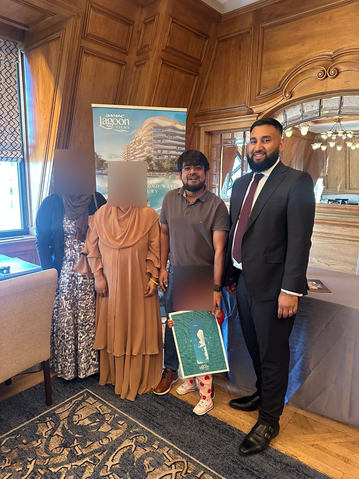 Tazz Miah with a family receiving their DAMAC Lagoon Views documents in London